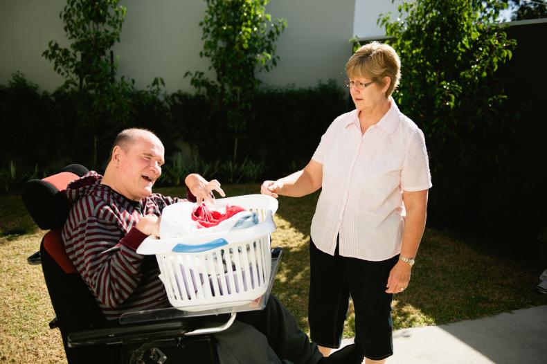 Disability worker helping a man with a disability to hang out the washing