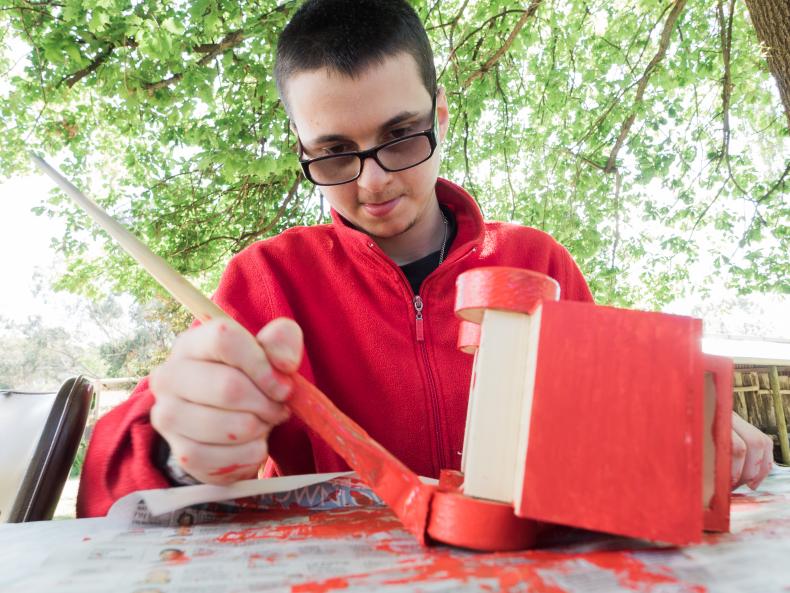 Man with disability painting a red toy truck