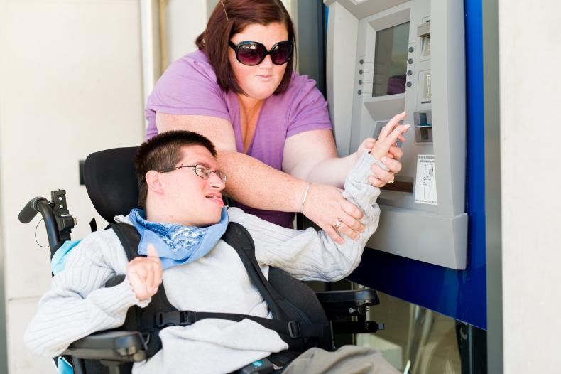 Disability worker assisting a person with disability at an ATM machine