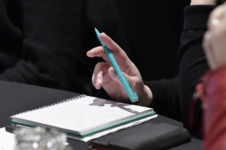 Person sitting at a table with a pen in hand